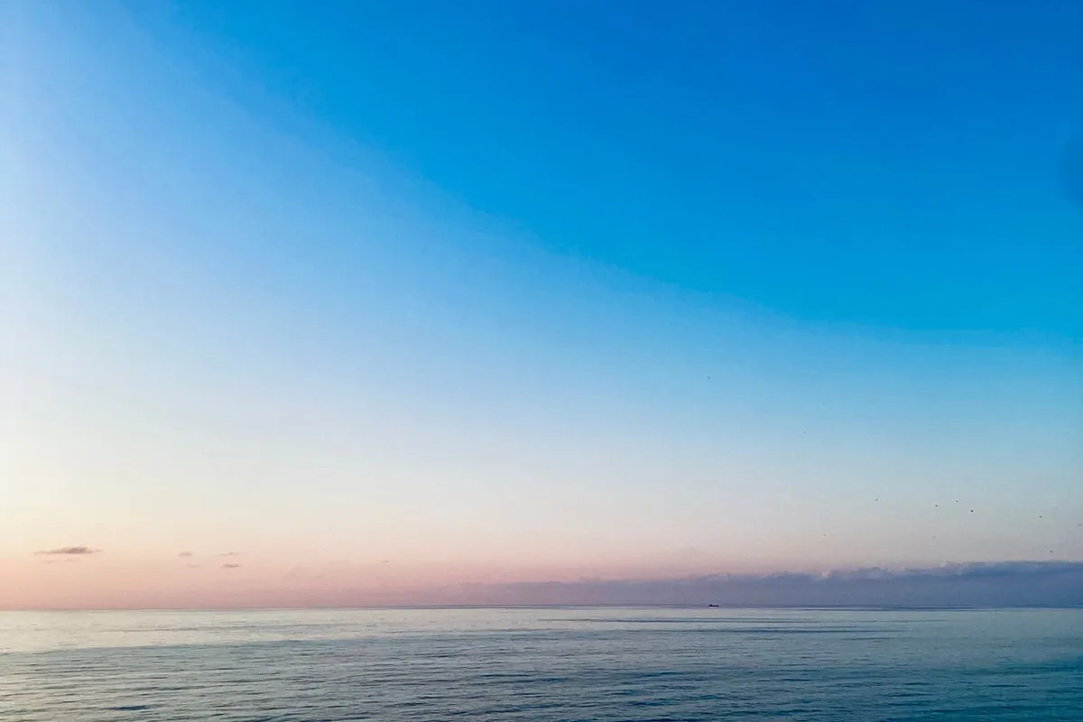 The first light of dawn over a calm ocean horizon at the end of the night