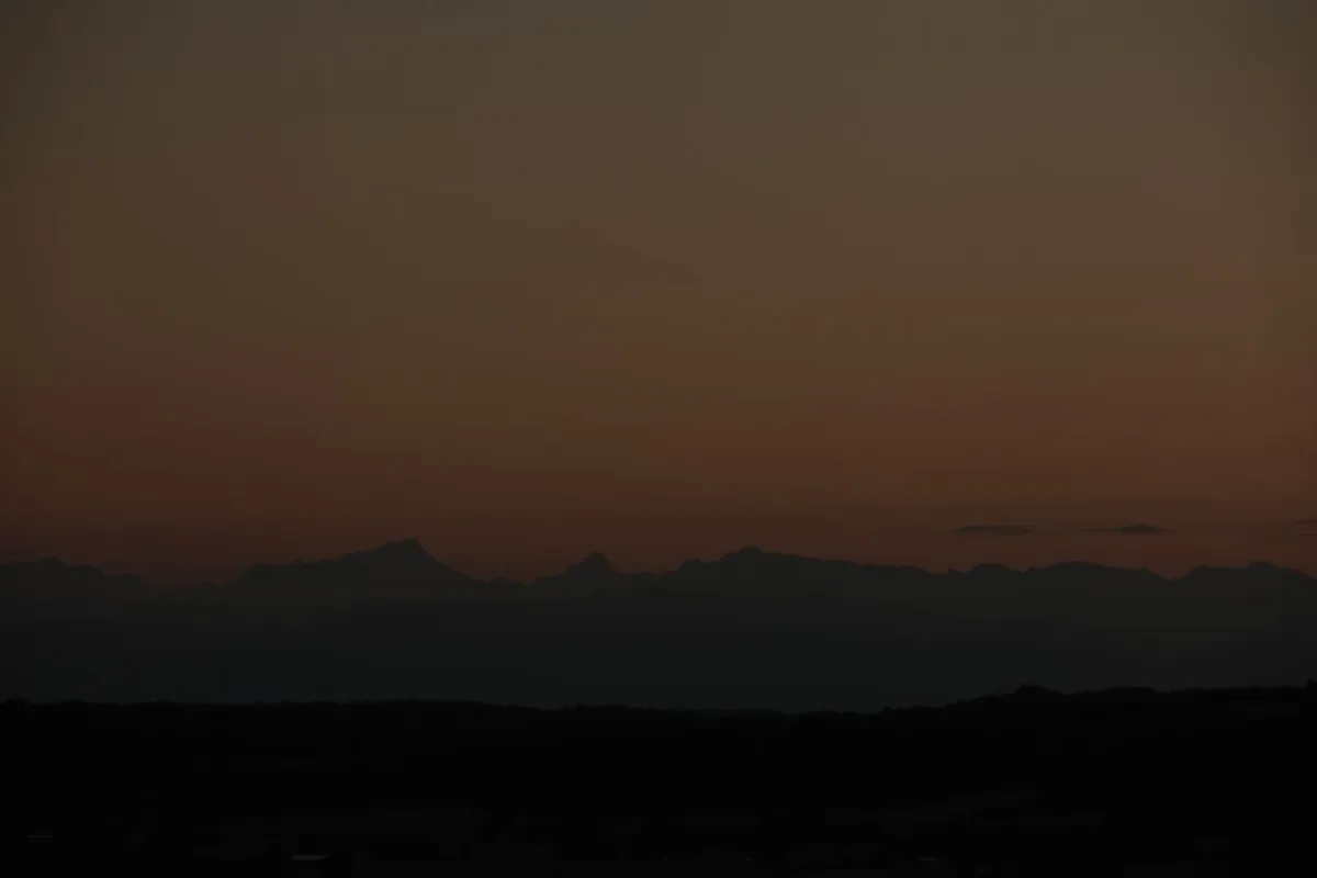 A pale band of first light on the horizon over dark hills, marking the end of the Tahajjud time