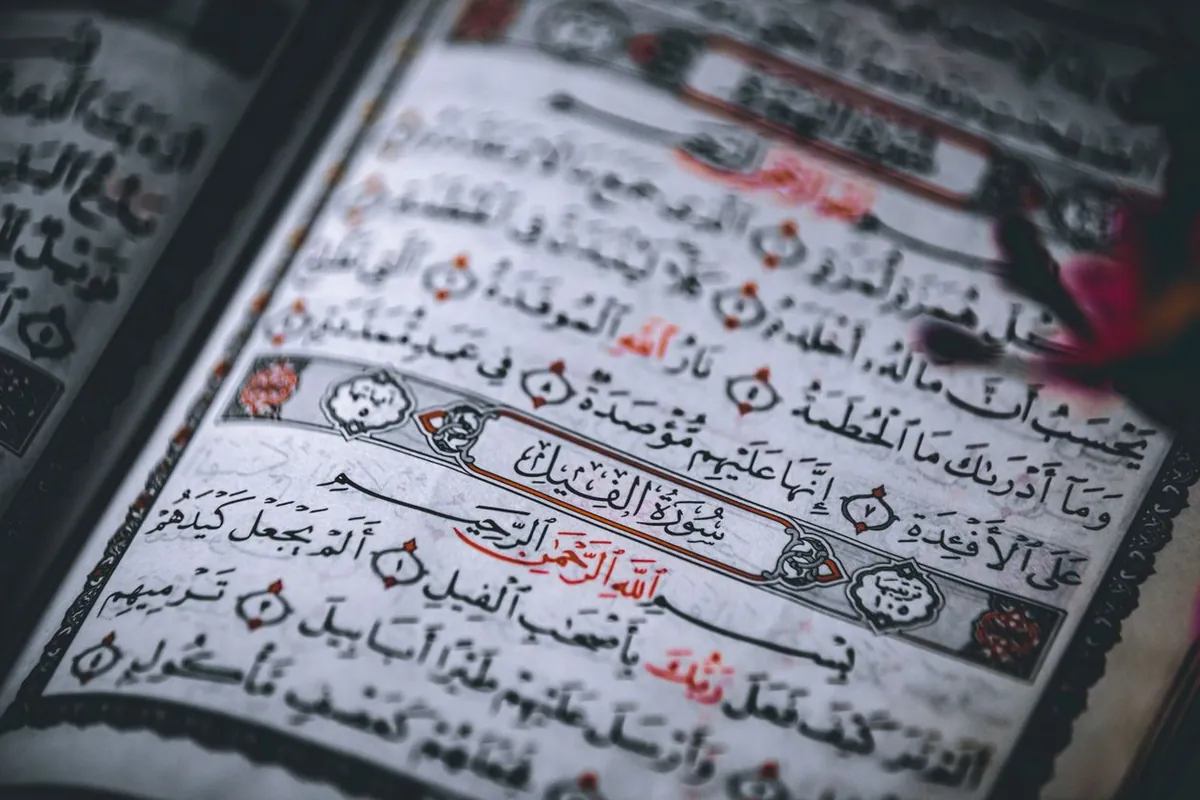 A close-up of an open Quran page, its Arabic calligraphy filling the frame